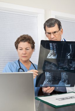 Doctor and Nurse Reading Spinal MRI Scan at the Computer clipart