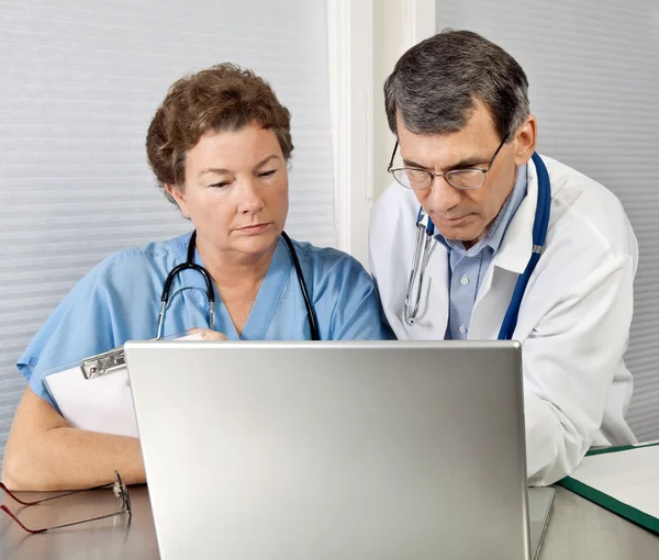 Revisión de médicos y enfermeras en la computadora portátil en la oficina —  Fotos de Stock