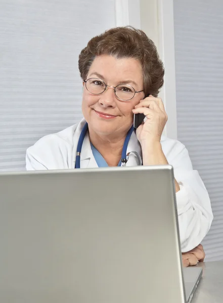 Kvinna läkare vid laptop, prata telefon — Stockfoto