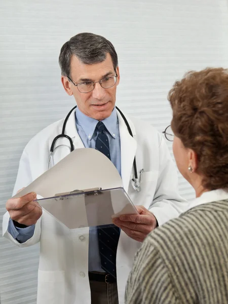 Médico discutiendo informe médico con paciente femenina — Foto de Stock