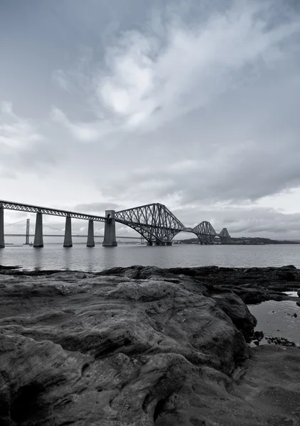 Black and White Forth Rail Bridge with foreground rocks in Scotland — Stock Photo, Image
