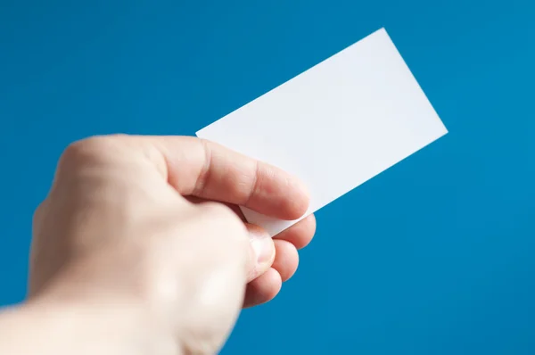 Mão segurando um cartão de visita vazio no fundo azul — Fotografia de Stock