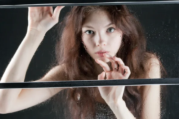 Портрет красивой девушки во влажном окне — стоковое фото