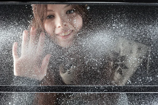 Молодая счастливая девушка за снежным окном — стоковое фото