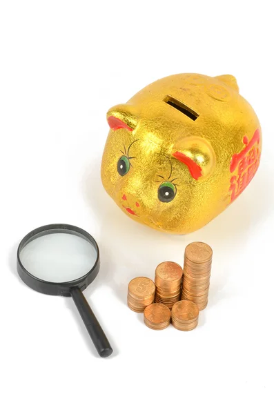Magnifier and piggy bank with coins — Stock Photo, Image