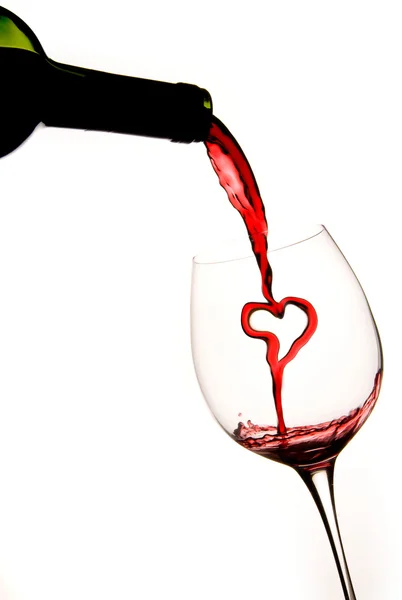Pouring a heart of red wine into a glass — Stock Photo, Image