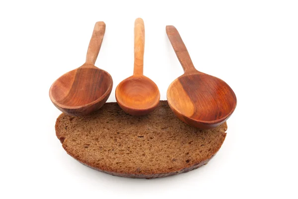 Skjeer av tre og et stykke brød – stockfoto