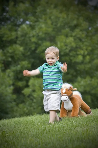 Hračka kůň pronásleduje chlapce — Stock fotografie