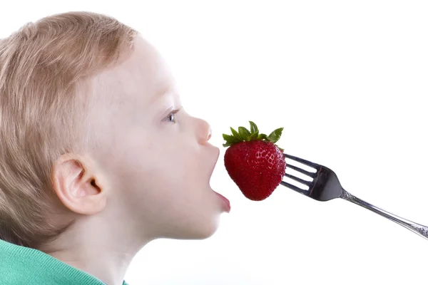 Junge isst Erdbeere — Stockfoto