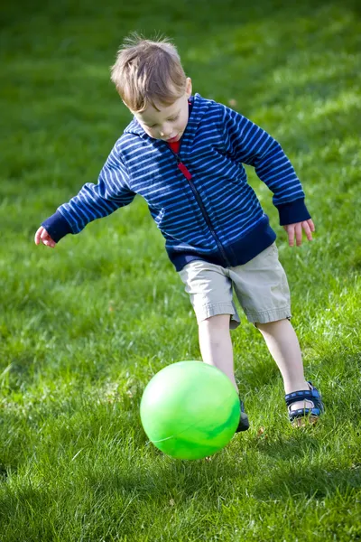 Мальчик пинает мяч — стоковое фото