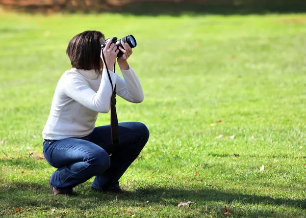 Mujer bonita agachándose con la cámara — Foto de Stock