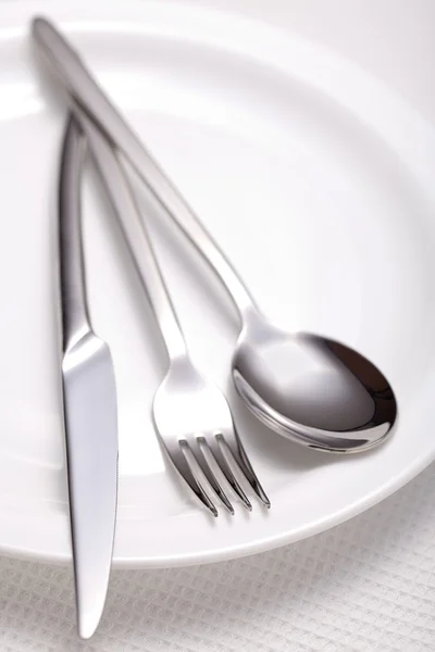 Vidlička, nůž, lžička a bílý talíř — Stock fotografie