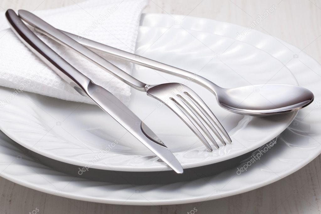 Fork, knife, spoon and a white plate