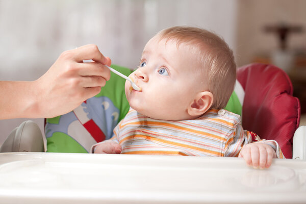 Mother feeding baby food to baby