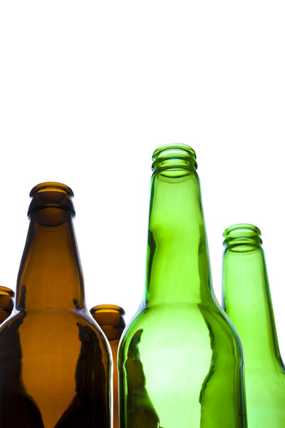 Looking up at empty green and brown beer bottles on a white background.