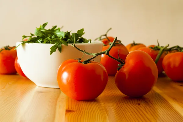 Tomates de vid y un tazón de hojas de cohete — Foto de Stock