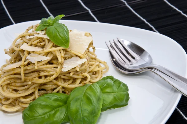 Heap of spaghetti with fresh pesto on dark background — Stock Photo, Image