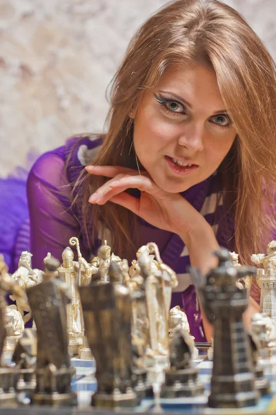 Mulher bonita deitada no chão e jogando xadrez — Fotografia de Stock