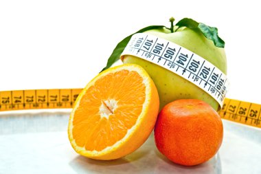 Orange, apples & mandarine measured by tape meter clipart