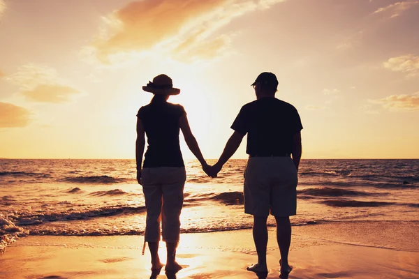 Старший пара, насолоджуючись захід сонця на пляжі — стокове фото