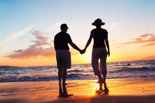 Старший пара, насолоджуючись захід сонця на пляжі — стокове фото