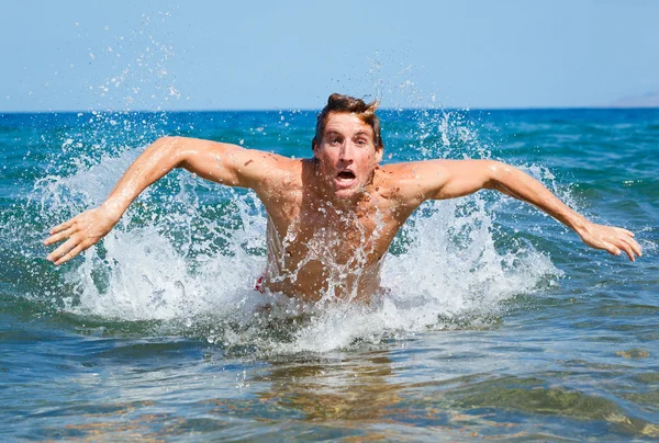 Man swimming butterfly strokes in ocean — Stock Photo, Image