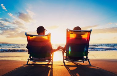 Senior couple of old man and woman sitting on the beach watching clipart