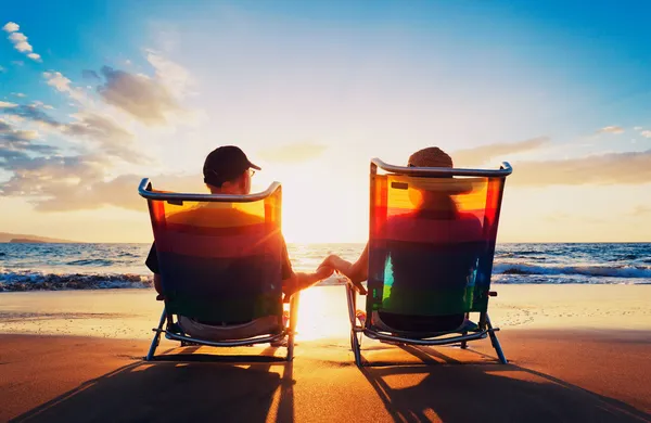 Senior paar alter Mann und Frau sitzen am Strand und beobachten lizenzfreie Stockbilder