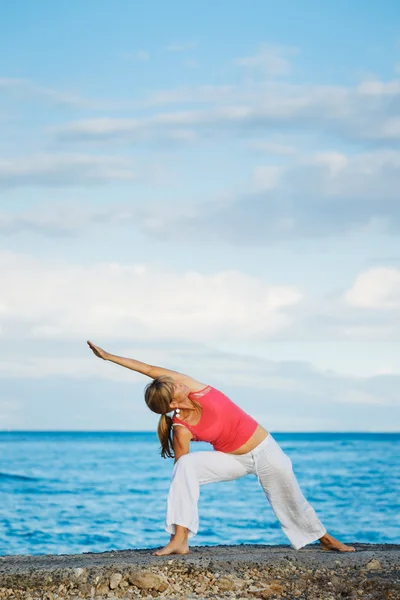 Schöne Yoga-Frau praktiziert Yoga am Meer — Stockfoto