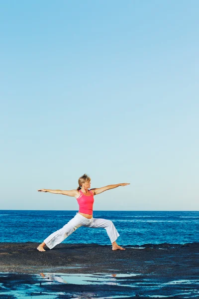 Schöne Yoga-Frau praktiziert Yoga am Meer — Stockfoto