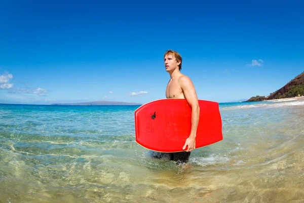 Mladý muž s prkno na pláži — Stock fotografie