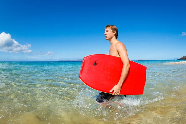 Молодой человек с доской для буги на пляже — стоковое фото