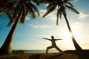 Gün batımında yoga yapan kadın.