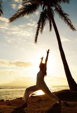 Gün batımında yoga yapan kadın.