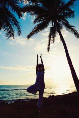 Gün batımında yoga yapan kadın.