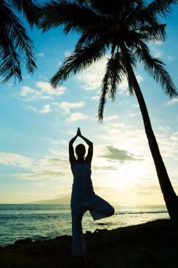 Gün batımında yoga yapan kadın.