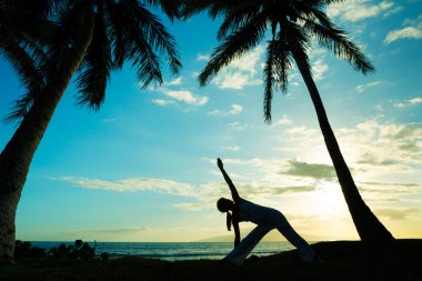 Gün batımında yoga yapan kadın.