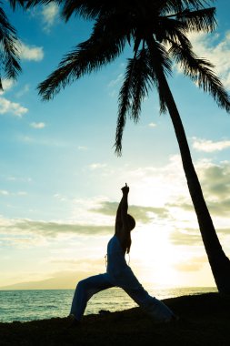 Gün batımında yoga yapan kadın.