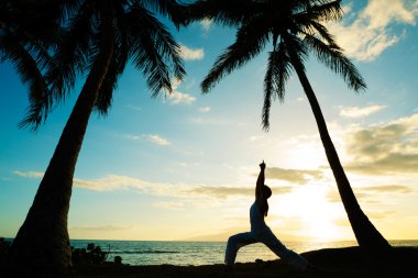 Gün batımında yoga yapan kadın.