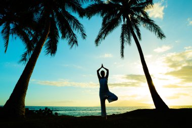 Gün batımında yoga yapan kadın.