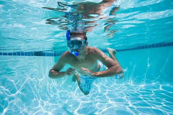 Молодой человек плавает под водой в бассейне — стоковое фото