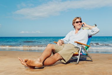 Business man calling by cell phone on the beach in Hawaii clipart