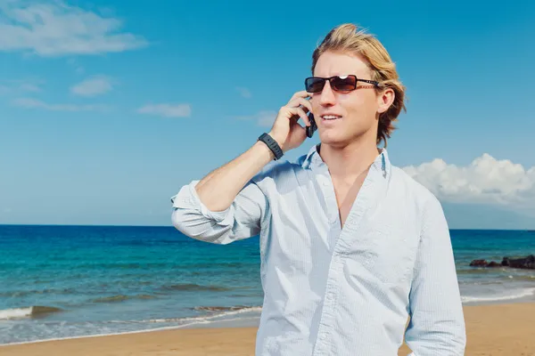Affärsman som ringer genom mobilen på stranden Royaltyfria Stockbilder