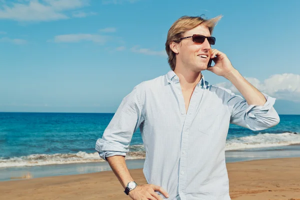 Affärsman som ringer genom mobilen på stranden Stockfoto