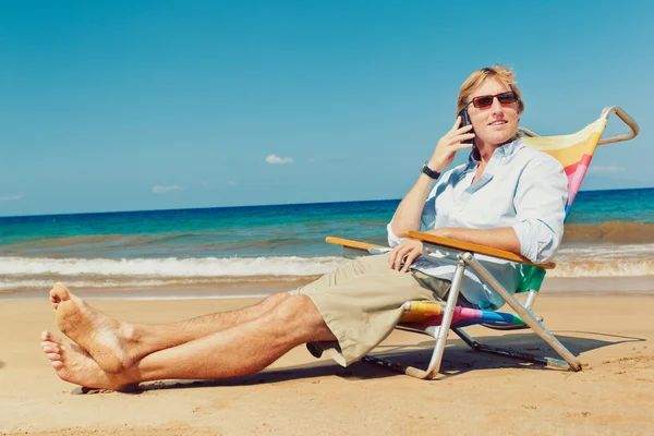 Zakenman bellen door cell phone op het strand in Hawaï Stockfoto