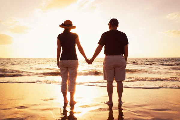 Старшая пара наслаждается закатом на пляже — стоковое фото