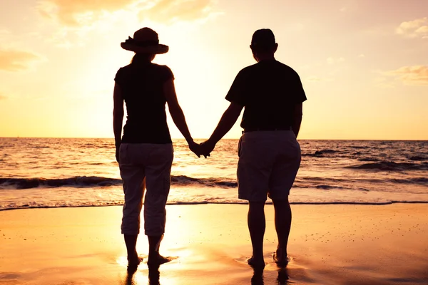 Äldre par njuter av solnedgången på stranden — Stockfoto