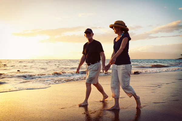 Idősebb pár élvezi a naplementét a strandon — Stock Fotó