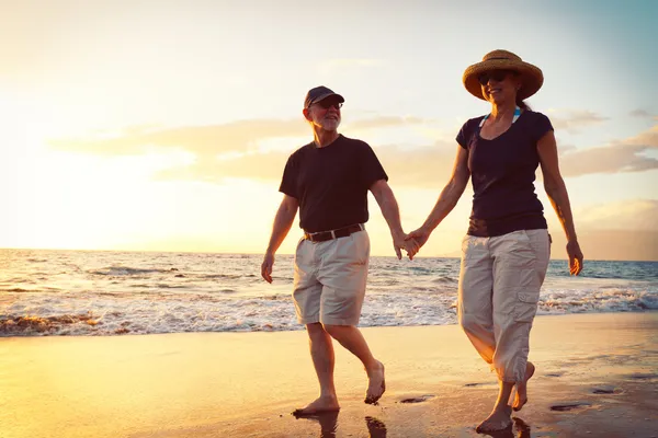 Pareja mayor disfrutando de la puesta de sol en la playa — Foto de Stock