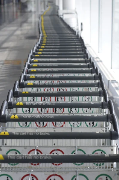 stock image Row of luggage carts along a window wall